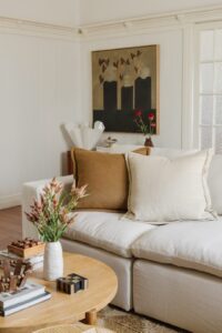 Looking into the corner of the lounge room through a coffee table styled with objects, over to an abstract artwork.