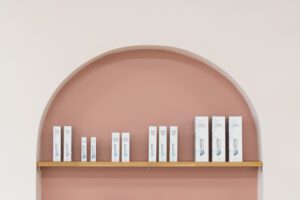 Boutique pink arched shelf with skincare products sitting on it.