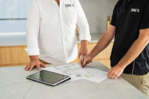 Two builders look at the house plans together.