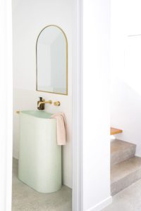A power room with an arch mirror and sage green vanity.