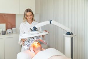 A nurse in a beauty clinic performs LED Healite therapy on a client.