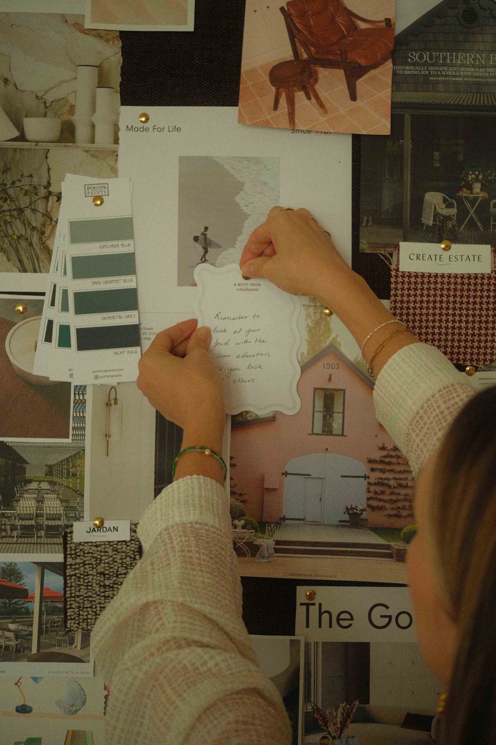 Hand placing quote onto a Inspiration Board and pinning it on.