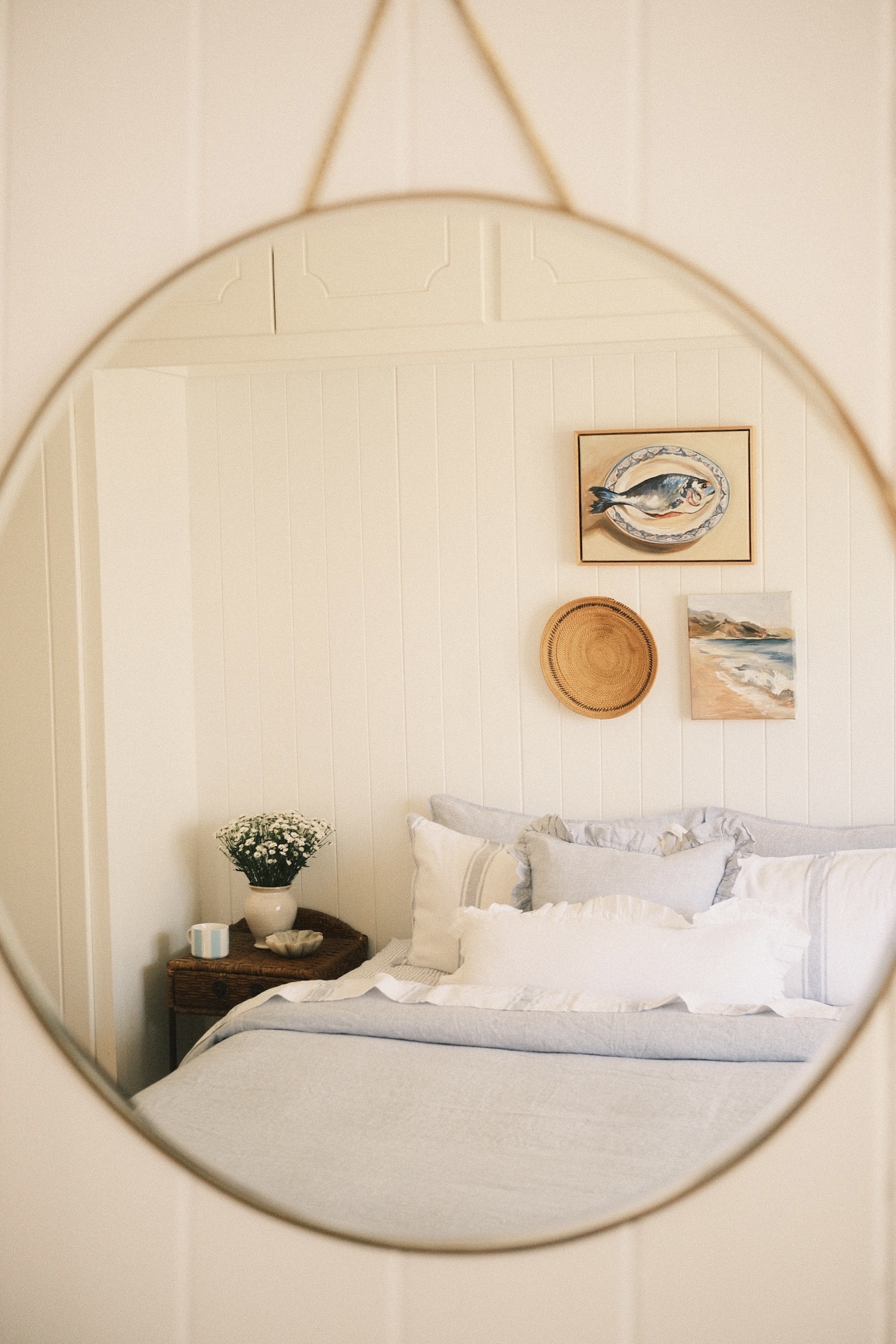 Primary bedroom of a country style Queenslander home displayed in the reflection of a circular mirror.