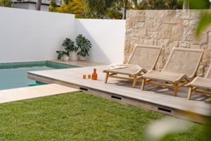 The pool area and deck at Holiday Haus, with sun-lounges and plants.