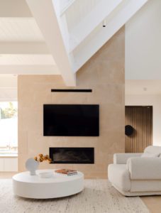 A stone fireplace with coffee table and arm chair.