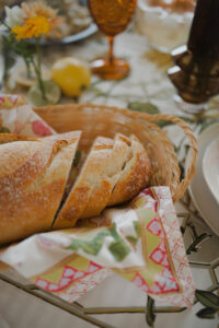 A close up of a sourdough loaf sliced up in a basket amongst a festive lunch spread.