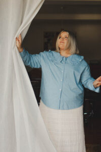 Hayley opens the studio door, pulling back the curtain while looking up.