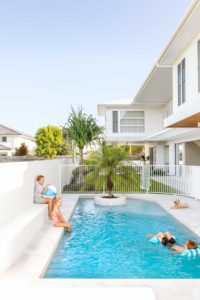 A modern pool with kids swimming and relaxing.