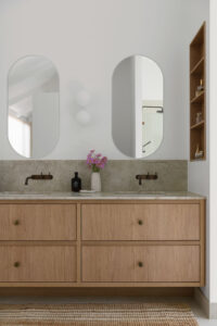 Two oval shaped mirrors over two sinks in the primary ensuite of a renovated country style Queenslander home.