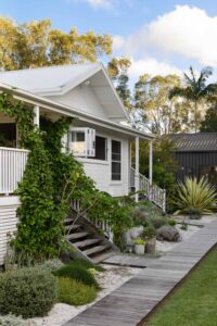 Angled exterior shot of a renovated white country style Queenslander home.