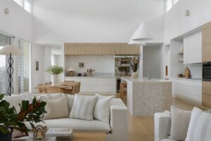A modern living room styled with Coco Republic furniture looking back towards bar and kitchen with MCM House pendants.