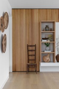 A modern indoor living space styled with wall baskets, ceramic shelf details and a vintage wooden chair.