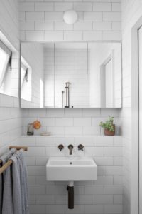 A modern bathroom with subway tiles and oak towel rail.