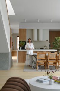 The homeowner stands alongside the dining table in a modern cottage.