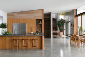 A modern dark timber kitchen with concrete floors.