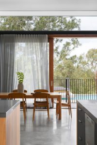 A modern dining room with concrete floors and walls with timber sliding doors.