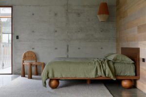 A modern bedroom with concrete floors and walls with a timber panel wall.