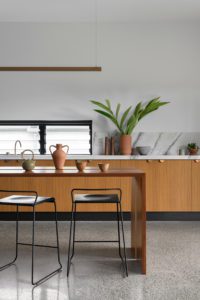 A modern kitchen with concrete floors and walls with a timber cabinetry.