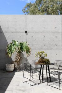 A concrete outdoor area with a black wire outdoor area and Pop and Scott pot.