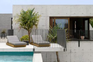 Two sun-lounges in front of a concrete pool area and house.