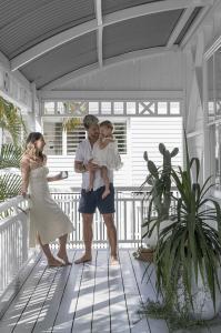 A couple relaxes with a cup of tea and their daughter on the verandah of their Queenslander.
