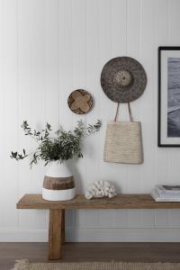Hats hang on the wall and a bench seat is used to display books and objects.