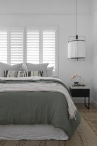 A sage green quilt with a linen pendant light.