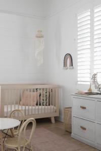 A children's nursery with a rainbow wall hanging and designer cot.