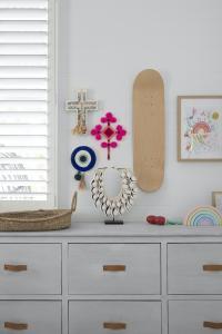 A kids nursery drawers with crosses, skateboards and art adorning the walls.