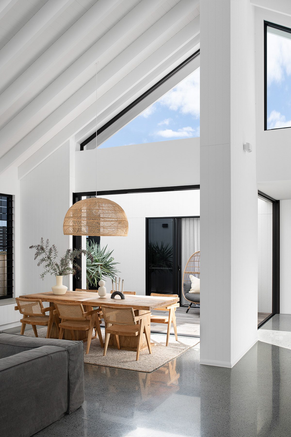 Interior of a home with concrete floors, white walls and an elmwood table and chairs.