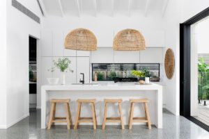 A modern kitchen with cane hanging pendants and elmwood stools.