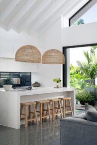 A modern kitchen with cane hanging pendants and elmwood stools.