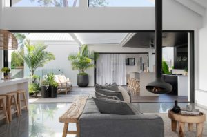 A hanging fireplace and grey lounge are pictured in a modern living room.