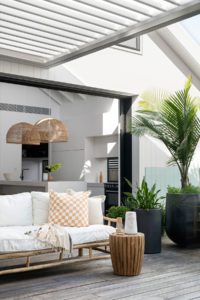 A cane lounge styled with a checkered cushion and throw.