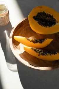 An aerial shot of cut pawpaw in a platter with a rattan styled drinking glass.