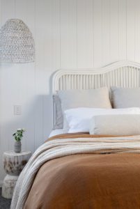 A cane bedhead and rust coloured bedlinen.