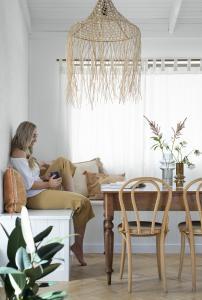 A homeowner sits at her vintage dining table with a cup of tea.