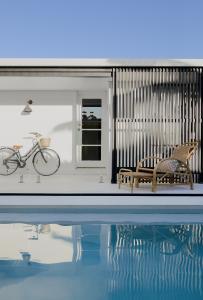 A cane sun-lounge is placed beside a pool.