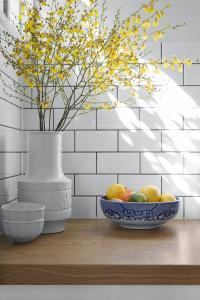 Yellow orchids in a vintage vase with a blue fruit bowl.
