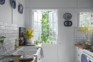 A kitchen window is open with yellow flowers in a vase sitting on the counter.