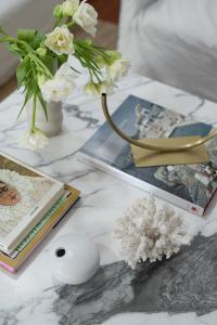 A marble coffee table is decorated by lots of objects and vases.