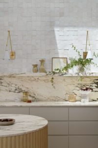 A modern kitchen with a marble backsplash, and styled open shelving.