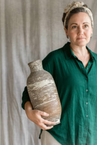 Ceramic artist Kerri of Nioka Clay holding a handcrafted marbled vase.