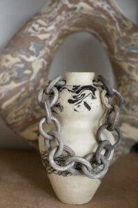 A close up of a marbled ceramic vase with chain linked handles in the home studio of Nioka Clay.