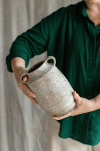 Ceramic artist Kerri of Nioka Clay holding a handcrafted speckled vase.