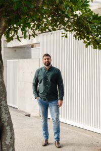Tyler from Sage Property stands in front of a white modern house.