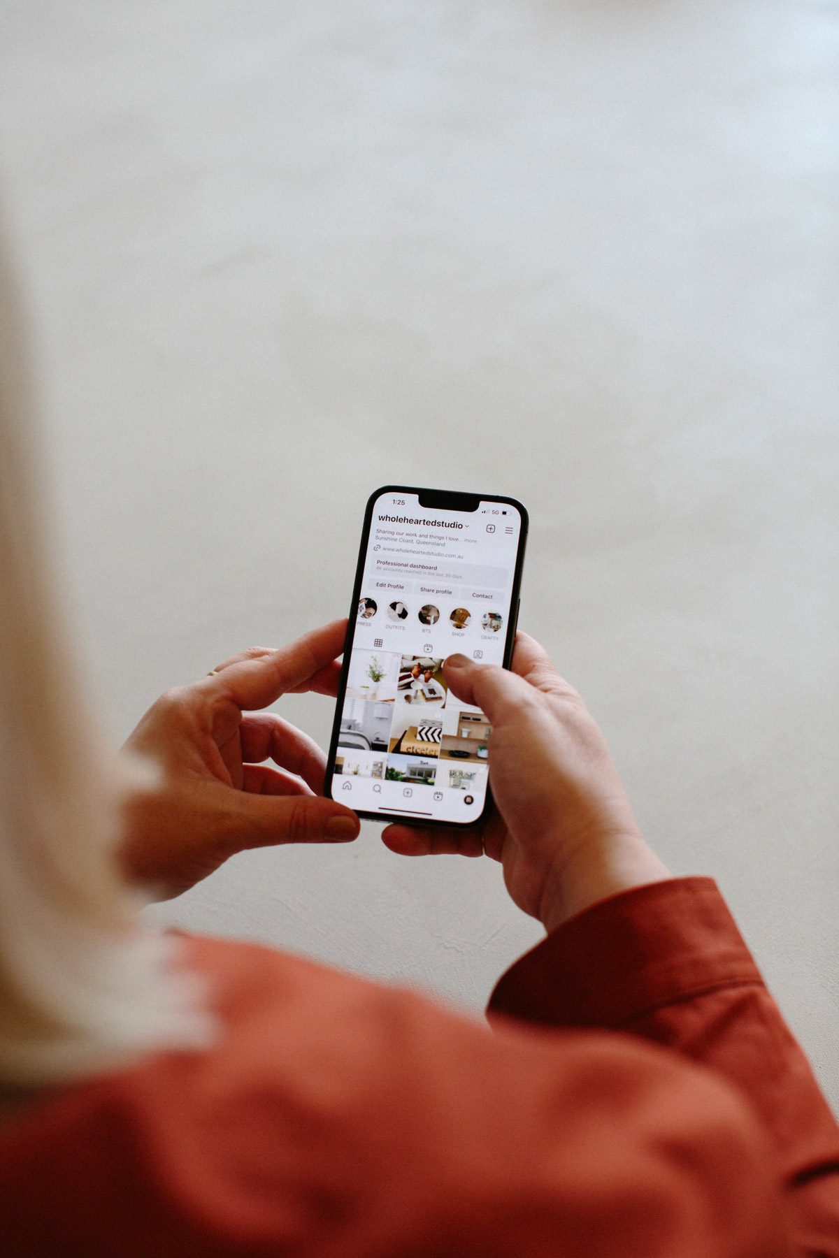 A close up of a phone in the hands of someone who is looking at an Instagram account.