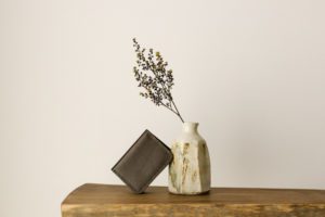 A handmade wallet styled with a ceramic vase made in Australia.