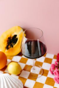 A monogrammed wine glass surrounded by flowers and fruit.