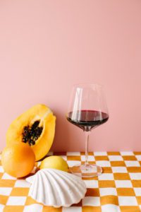 A monogrammed wine glass surrounded by fruit.
